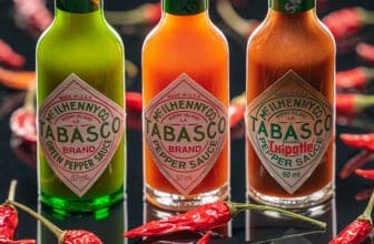 Drei Tabasco Flaschen und Chilis