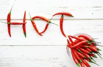 Rote Chilschoten, die zum Wort Hot geformt wurden neben weiteren Schoten