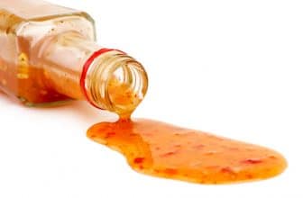 Pikante Sauce, die aus liegender Glasflasche läuft.