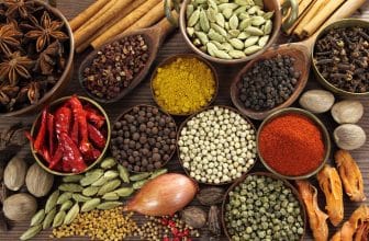 Gewürze und Kräuter in Metallschalen sowie Holzlöffel