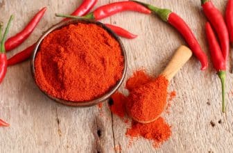 Rotes Chilipulver in Schälchenneben ganzen Schoten