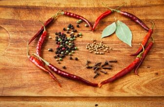 Getrocknete Chillischoten, die zu einem Herz gelegt wurden mit Gewürzen in der Mitte