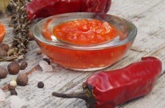 Glasschüssel mit Chilisauce, daneben rote Chilischote